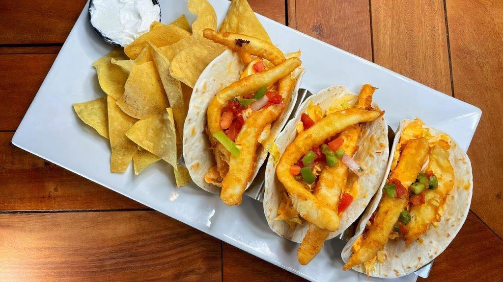 Fish Tacos · Our white fish, blackened or deep-fried, served inside three soft flour taco shells topped with a spicy shredded lettuce slaw and garnished with salsa. Served with sour cream on the side and a side of tortilla chips.
