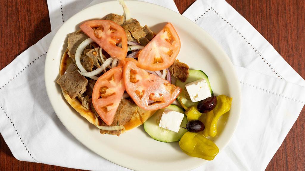 Gyro Plate · Gyro meat, freshly cut off the spit, tomatoes, onions, olives, feta cheese and cucumber sauce, on an open face pita.