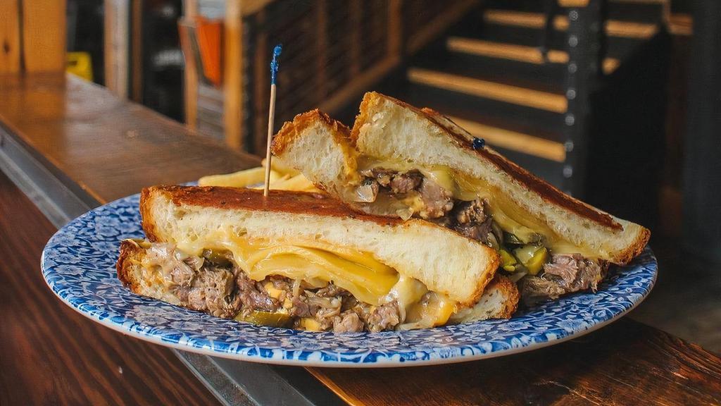 Grilled Cheese Beef Tosti · Shredded slow-cooked beef, smoked gouda, honey glazed onions, sliced jalapeno, on fluffy challah bread.