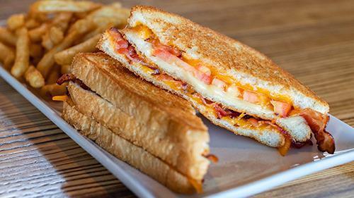 Ultimate Grilled Cheese · A doubled stacked grilled cheese loaded with Cheddar, Monterey Jack and Swiss cheese, crispy bacon and fresh sliced tomatoes grilled on buttered white bread.
