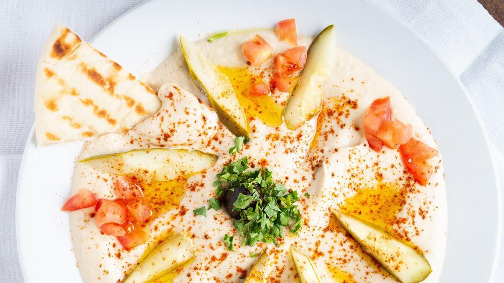 Hummus With  Pita · Garbanzo beans, tahini sauce, lemon juice,
paprika & garlic. Topped with chopped onion,
tomato, olive oil & olives. Consuming raw or under cooked meats, poultry, seafood, shellfish or eggs may increase your risk of food borne illness