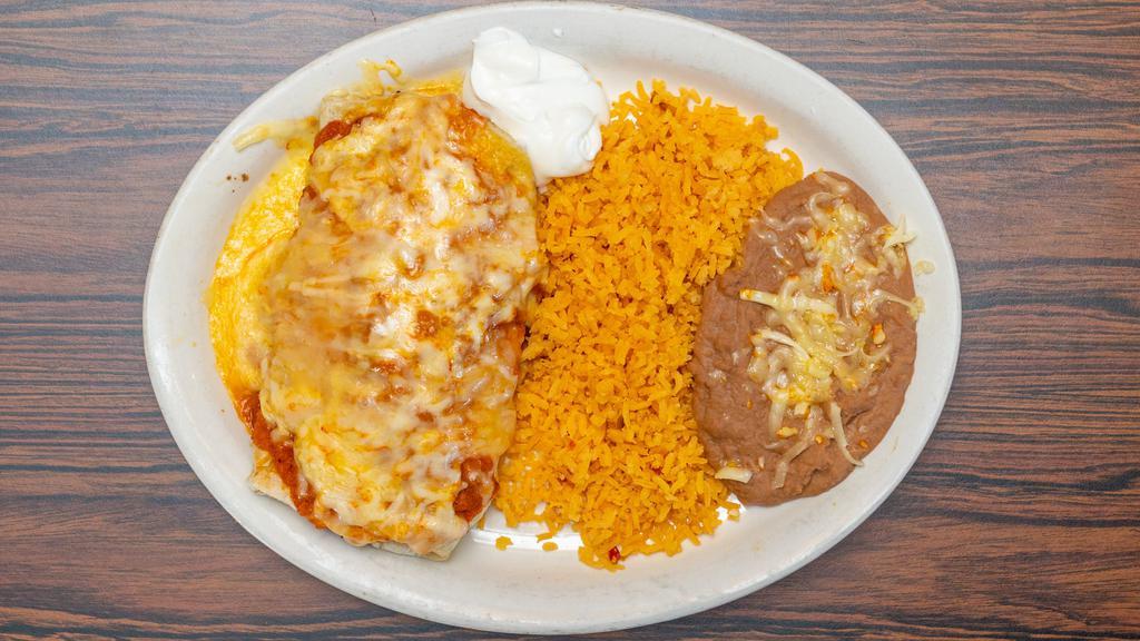 Burrito Suizo Dinner · Contains beans, lettuce, tomato, cheese, onions, cilnatro and sour cream. Served with ranchera sauce, melted cheese on top with rice and beans on the side.