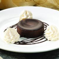 Chocolate Flourless Cake · A rich and decadent flourless cake, topped with chocolate ganache. Served atop chocolate sau...