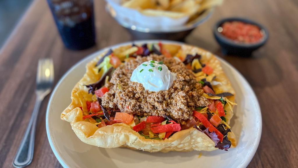 Taco Salad · A crisp tortilla bowl filled with fresh mixed greens, and shredded cheese. Topped with tomatoes, sour cream, chives, and Southwestern croutons.