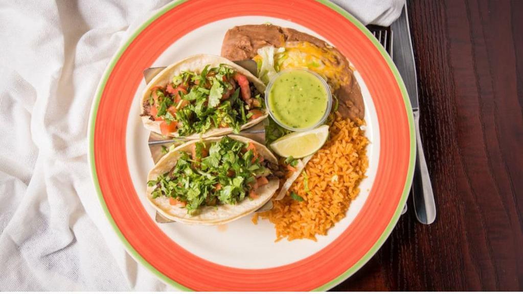 Baja Tacos · Two soft tacos with grilled steak, onions, jalapenos, bacon, pico de gallo, and fresh chopped cilantro on corn tortillas. Served with refried beans, Mexican rice, avocado sauce, and a lime wedge.