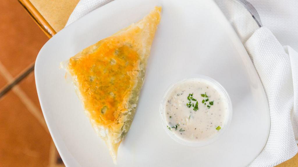 Spanakopita · Chopped spinach, diced onions and feta cheese. Served in a flaky puffed shell with house dressing.