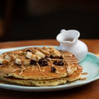 Curious George Hotcakes · Two hotcakes filled with chocolate chips and bananas and topped with peanut butter cream