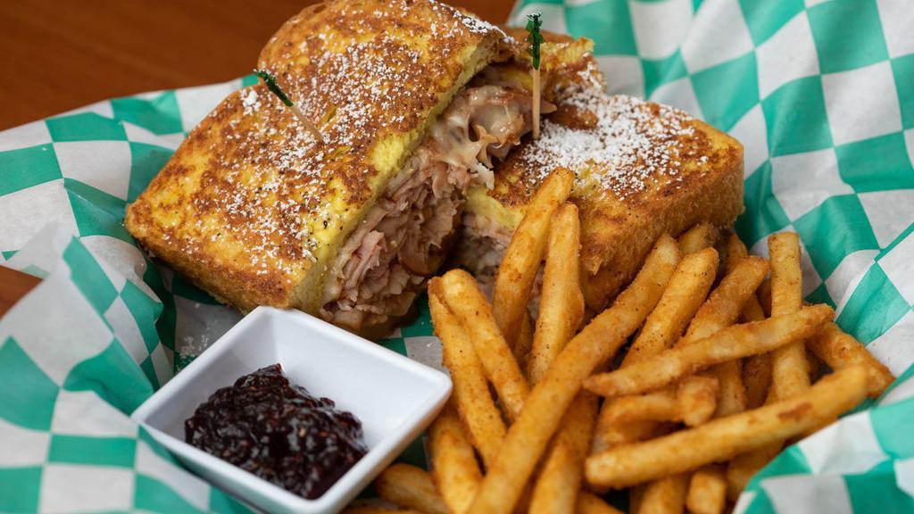 Monte Cristo · Ham, Turkey, and Swiss in between two pieces of french toast topped with powdered sugar and served with raspberry preserves