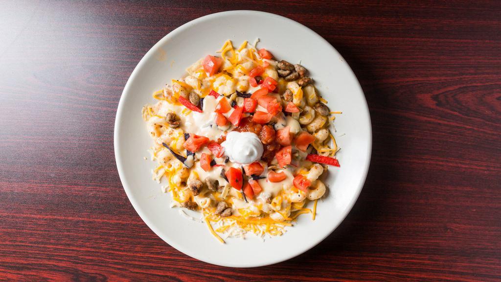 Taco Mac · Seasoned beef mixed in with our homemade Mac & Cheese topped with tomato's, tortilla strips, a little salsa and sour cream.  Then we drizzle queso across the top of it.  Add jalapenos to spice it up a bit.
