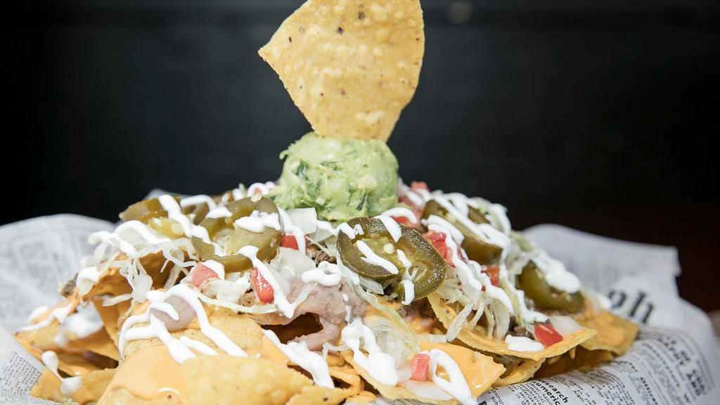 Super Nachos · Tortilla chips topped with choice of meat, beans, cheddar cheese, onion, tomato, guacamole, sour cream, and jalapeño peppers.