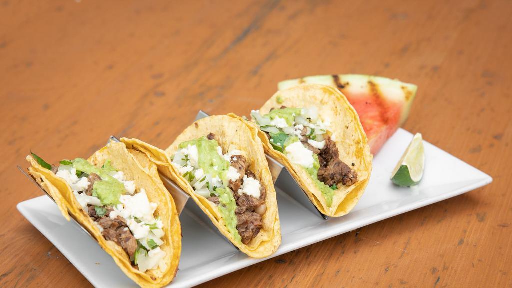 Barbacoa Beef Tacos · Corn tortillas, onion, cilantro, salsa Verde, Queso fresco.  Served with a wedge of grilled watermelon.
