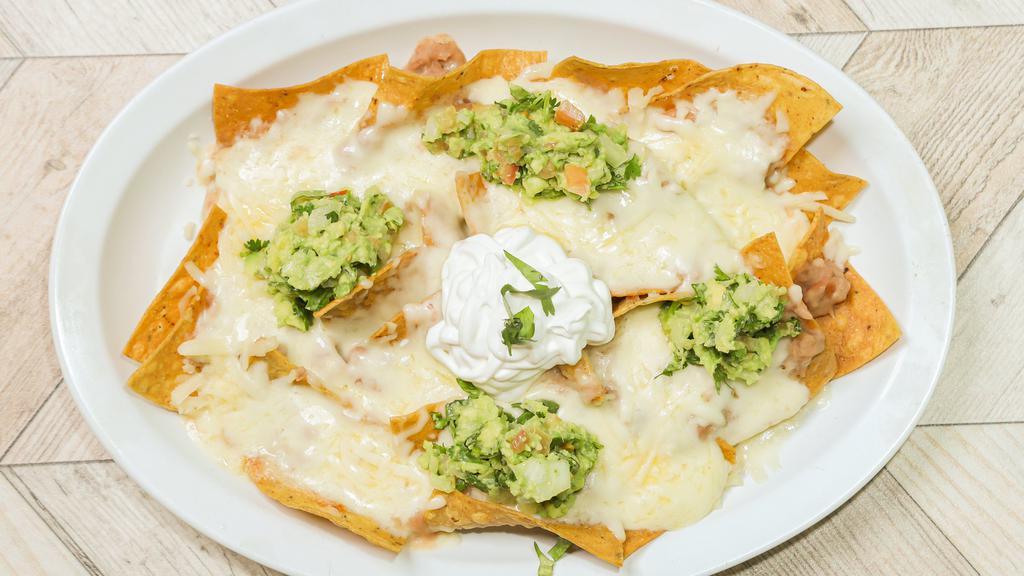 Nachos · A bed of crunchy tortilla chips caked in melted cheese with beans, cheese, sour cream and guacamole.