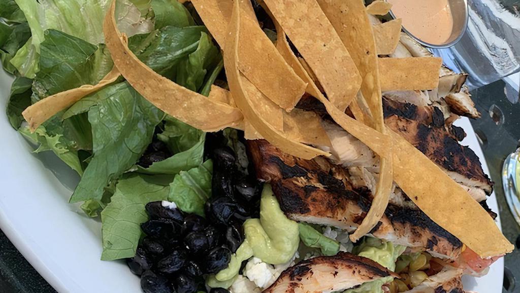 Southwest Chicken Cobb · Ancho lime grilled chicken black beans, tomato-com salsa, queso fresco, crunchy com tortilla strips avocado crema and a side of chipotle ranch dressing on a bed of romaine lettuce.
