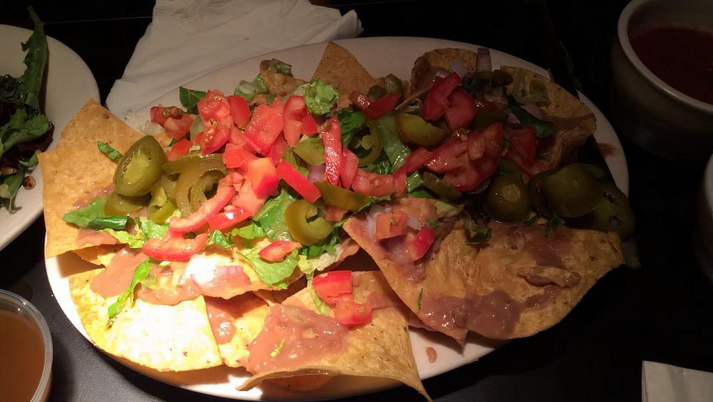 Nachos · Homemade tortilla chips, cheese, refried beans, onions, tomatoes, jalapenos, sour cream, guacamole.