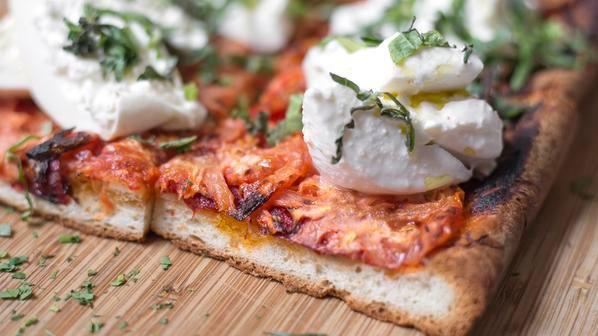 Dragona  · Baked with tomatoes and olive oil, then taken out of the oven and topped with burrata and fresh basil.