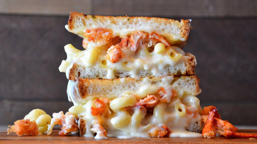 Lobster Mac Grilled Cheese · White cheddar mac and cheese topped with lobster claw meat, provolone and mozzarella cheese on artisan bread with garlic butter.