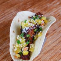 Pork Ribs Taco · Slow roasted rubbed ribs with a chili lime glaze, pineapple salsa, cilantro, and cotija chee...