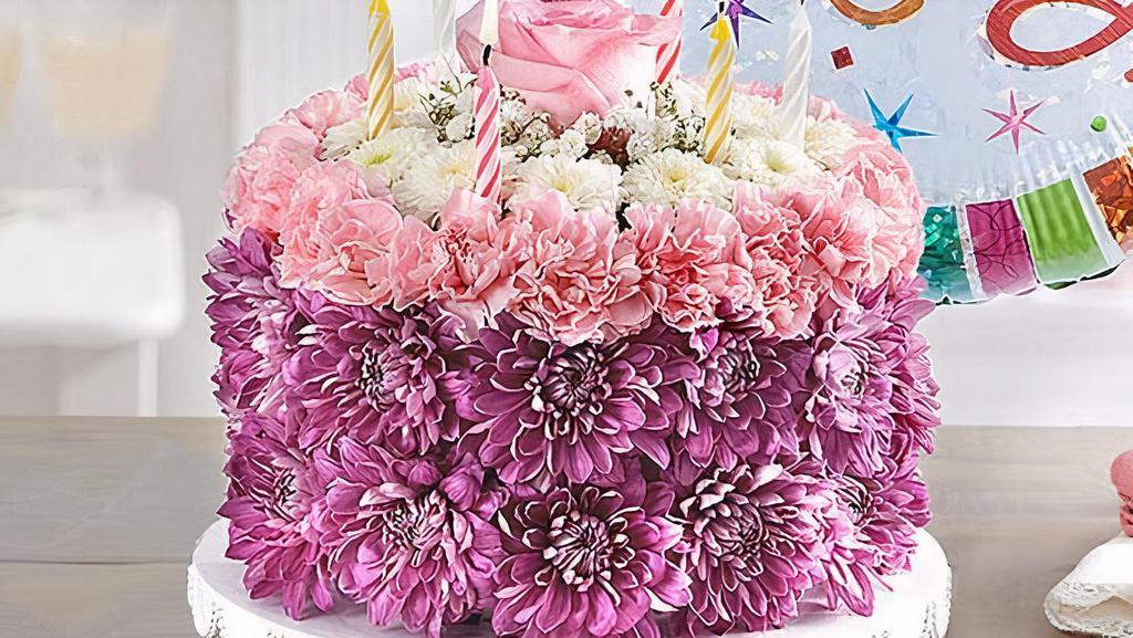 Birthday Wishes Flower Cake - Large · Flower cake is decorative only; DO NOT EAT.

3-D cake-shaped floral arrangement with pink mini carnations, lavender cushion poms, white button poms and baby’s breath; topped with a single pink rose and candles.
Large arrangement measures approximately 5.5