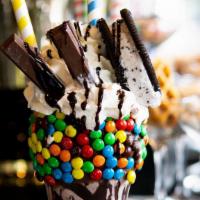 The Bodega · milk chocolate icing rim rolled in multi-colored M&M's, chocolate drizzle, triple chocolate ...