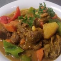 Curry Goat · Goat slow cooked with turmeric, garlic potatoes, ginger, bell peppers, onions and dumplings.