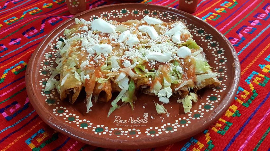 Enchiladas Rojas · Three rolled corn tortillas with shredded beef topped with red sauce and served with lettuce, avocado, and rice.