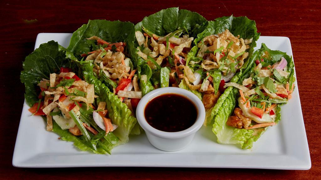 Thai Chicken Lettuce Wraps · Our fresh Asian slaw tossed in sesame lime with Thai peanut chicken. Topped with crispy wontons, diced red peppers, cilantro, and served on fresh romaine hearts. Accompanied by a side of spicy ginger sauce.
