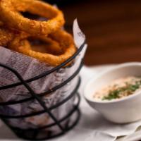 Tavern Onion Rings · Slices of sweet yellow onion dipped in batter and golden fried. Served with seasoned sour cr...