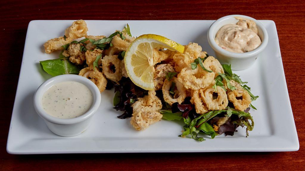 Lemon Basil Calamari · Tender calamari lightly fried for a delicate crunch. Set on a bed of spring greens and finished with basil chiffonade and lemon. Accompanied by lemon aioli and sun dried tomato aioli.