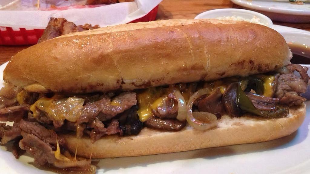 Prime Rib Sandwich · Thin slices of prime rib with grilled onions, green peppers and mushrooms. Topped with Cheddar cheese and served on a hoagie bun with au jus on the side for dipping.