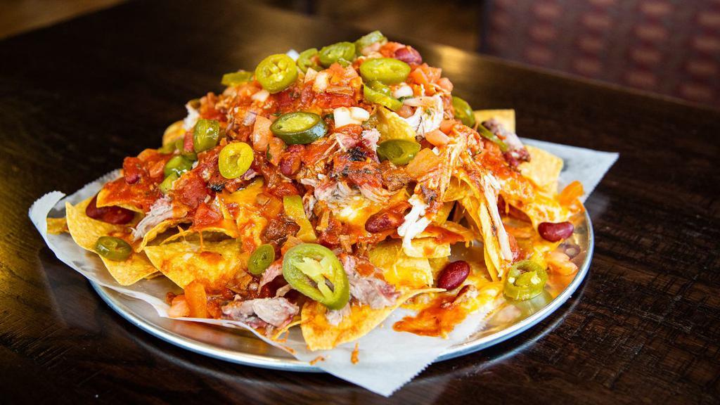 Pulled Pork Nachos · Tortilla chips covered in melted mild cheddar and Monterey jack cheese, smothered with smoked brisket chili and our slow smoked, delicious pulled pork. A side of jalapeños, salsa, and sour cream.