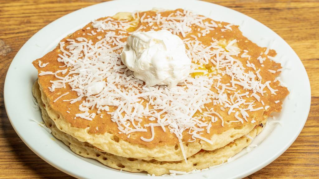 Piña Colada · Two pancakes with coconut and pineapple, topped with whipped topping.