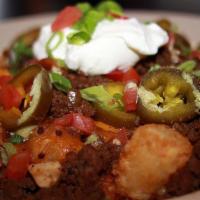 Irish Nachos · Tater tots topped with corned beef, tomato, corn, jalapeño, black beans, sour cream, beer ch...