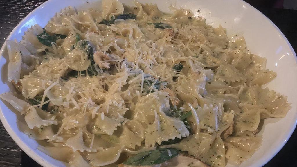 Pesto Farfalle · Grilled marinated chicken with creamy pesto sauce and bow-tie pasta topped with Parmesan cheese, spinach, diced tomatoes and rd onion