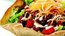 Taco Salad · Homemade tortilla shell filled with crisp garden greens, topped with taco meat, Cheddar, and...