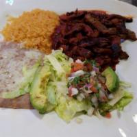 Chile Colorado · Tender sliced skirt steak simmered in Colorado sauce and served with rice, beans, lettuce, p...
