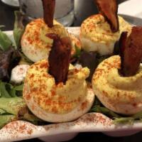 Deviled Eggs · Hard boiled eggs filled with whipped yolks and topped with paprika and pecan smoked bacon.