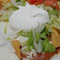 Nachos Supremo · Tortilla chips topped with ground beef, shredded chicken, and beans, all covered with lettuc...