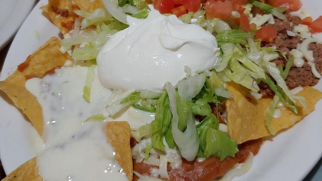 Nachos Supremo · Tortilla chips topped with ground beef, shredded chicken, and beans, all covered with lettuce, chopped tomatoes, and sour cream. Add guacamole for an additional charge.