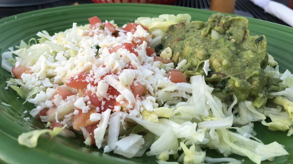 Guacamole Salad · This deliciosa Mexican salad is served with lettuce, tomatoes, guacamole, and shredded cheese.
