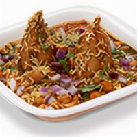!Samosa Chole. · Two samosas mashed and topped with tangy chole, chutneys, onions, sev and spices.