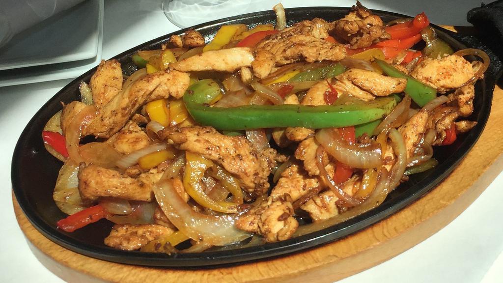 Vegan Fajitas · Soy protein strips, red, yellow, green peppers, tomatoes, onions, garlic, served in a sizzling cast iron skillet. Guacamole, pico de gallo, frijoles.