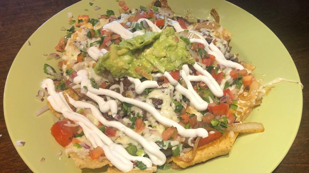 Nachos · Vegetarian. Melted cheese and refried beans on a bed of warm chips, topped with lettuce, tomato, sour cream, guacamole and pickled jalapeños/carrots