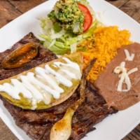 Carne Asada Tampiqueña · Grill skirt steak, marinated with with peppers, onion, guacamole, rice, beans, lettuce and t...