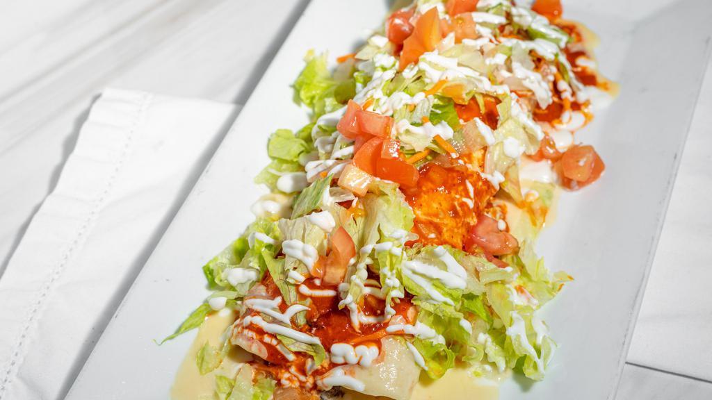 Burrito Azteca · Filled with ground beef or shredded chicken, topped with cheese sauce and tomatillo, lettuce, sour cream and tomatoes, served with rice and beans.