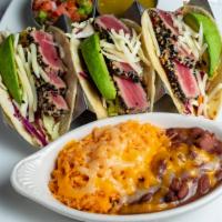 Seared Ahi Tuna Tacos · Three corn tortillas, lettuce, Monterey jack cheese, avocado, and ginger-soy dressing. Serve...