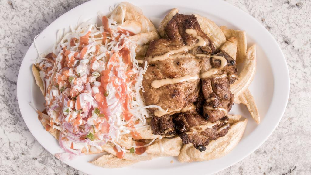 Chuleta Con Tajadas / Pork Chop With Sliced Plantain · Chuleta frita. Servida con tajadas de guineo con chimol, cebolla, repollo y aderezo. / Fried pork chop. Served on a bed of sliced plantains, comes topped with our typical Honduran dressing, shredded cabbage and sliced onion.