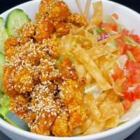Thai High Chicken Salad · Sweet and spicy thai fried chicken on a bed of greens paired with cucumbers, wontons and tom...