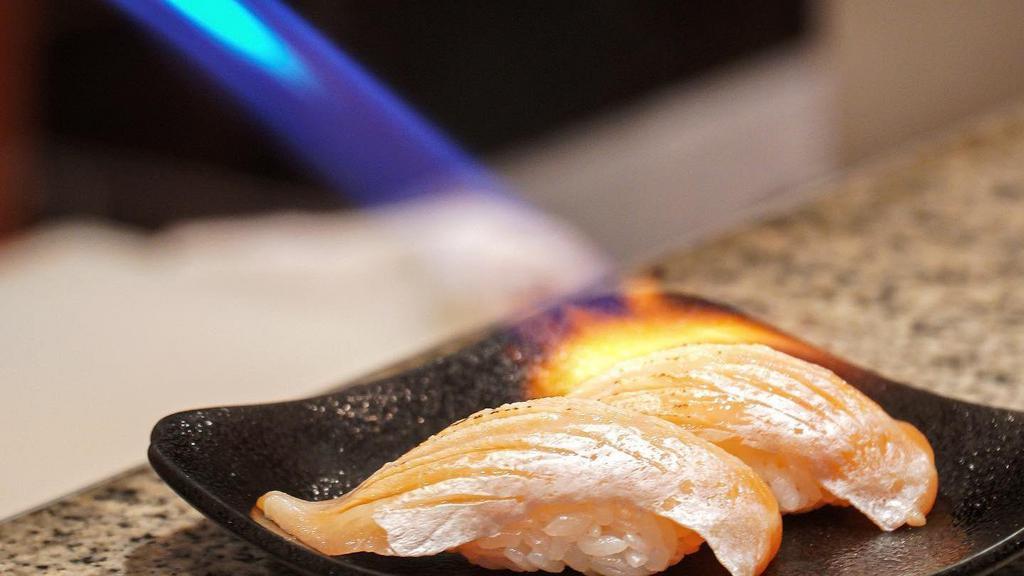 Torched Salmon Nigiri · Two pieces, Open flame, torched salmon nigiri topped with cilantro, house sauce, masago & togarashi.