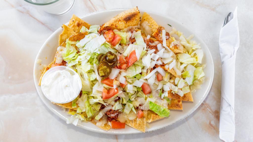 Nacho Supreme · Served with refried beans, choice of meat, melted cheese, topped with lettuce, tomato, onions, avocados, jalapenos, and side of sour cream.