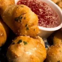 Garlic Knots (8 Pcs) · Tossed in garlic and parsley infused olive oil, topped with grated Parmesan, red sauce dip.